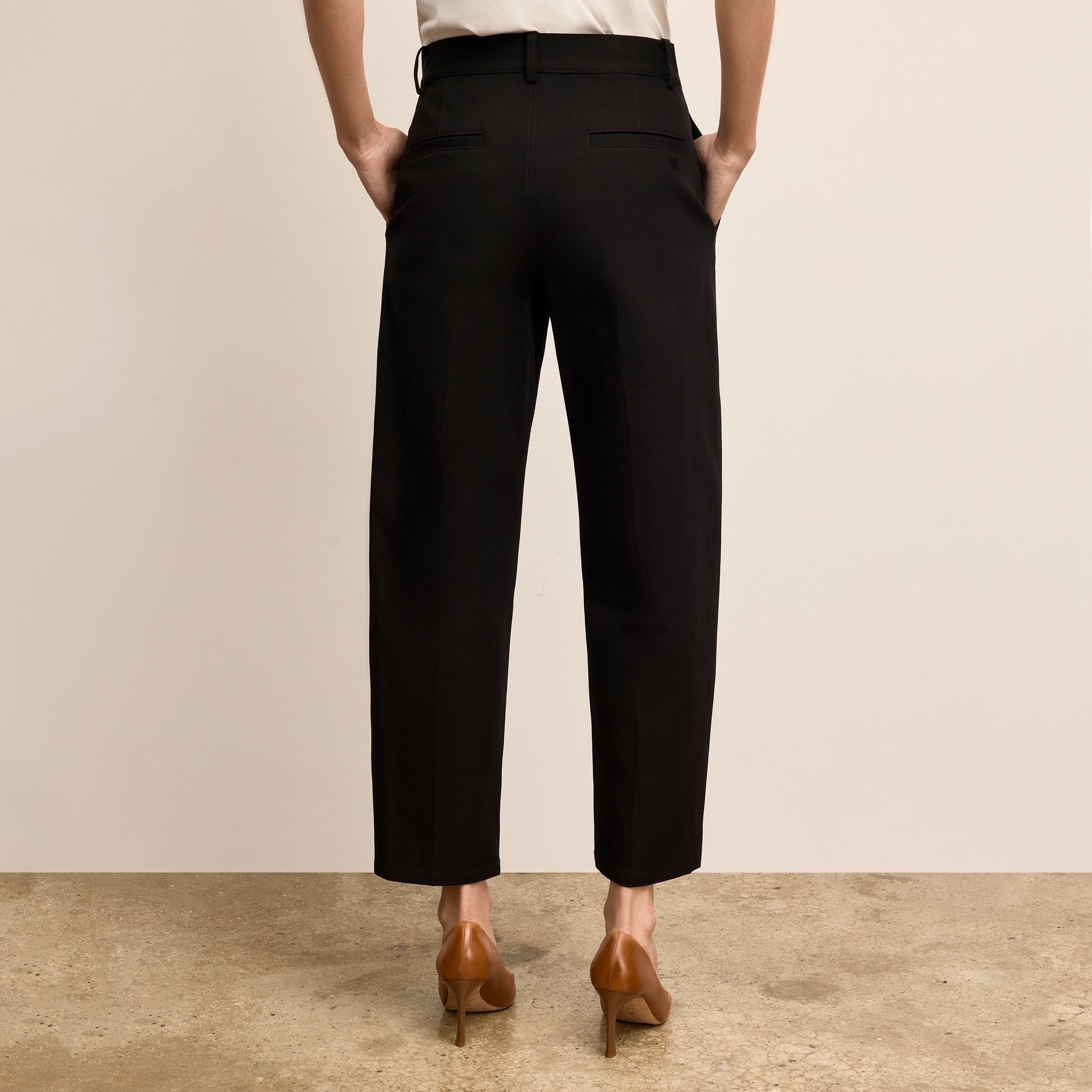 Person wearing black pants with a beige background