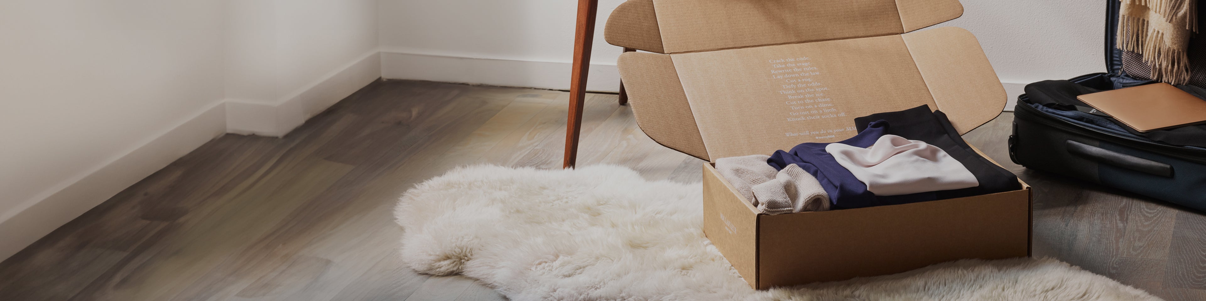 Box with clothes on a rug next to an open suitcase