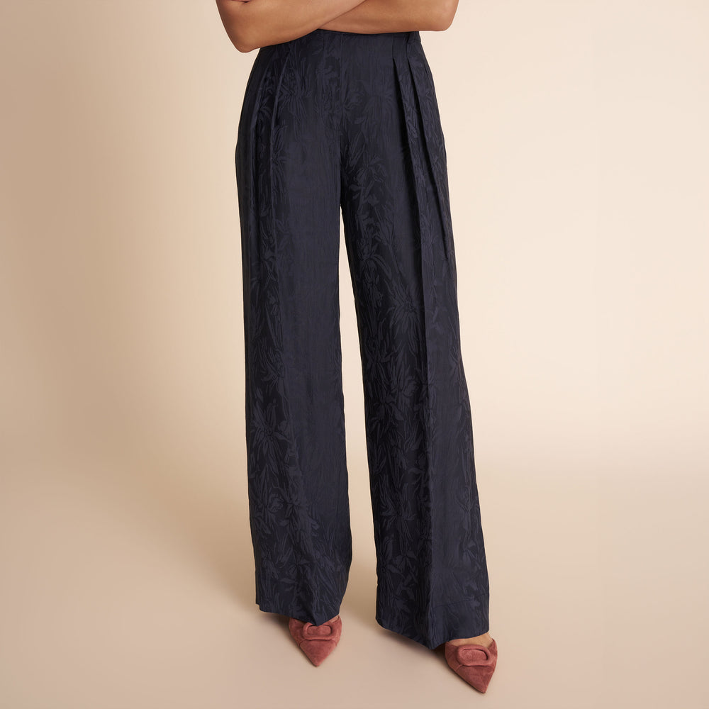 Navy blue wide-leg pants worn by a person on a beige background