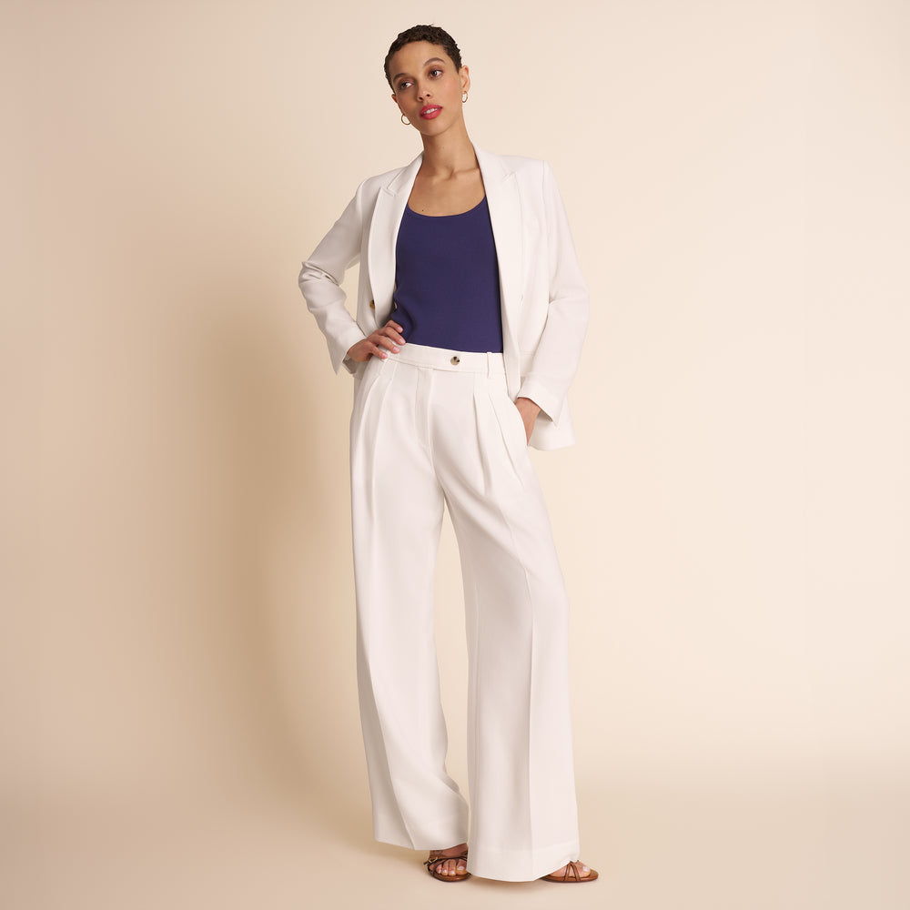 Woman wearing a white outfit with a purple top on a beige background