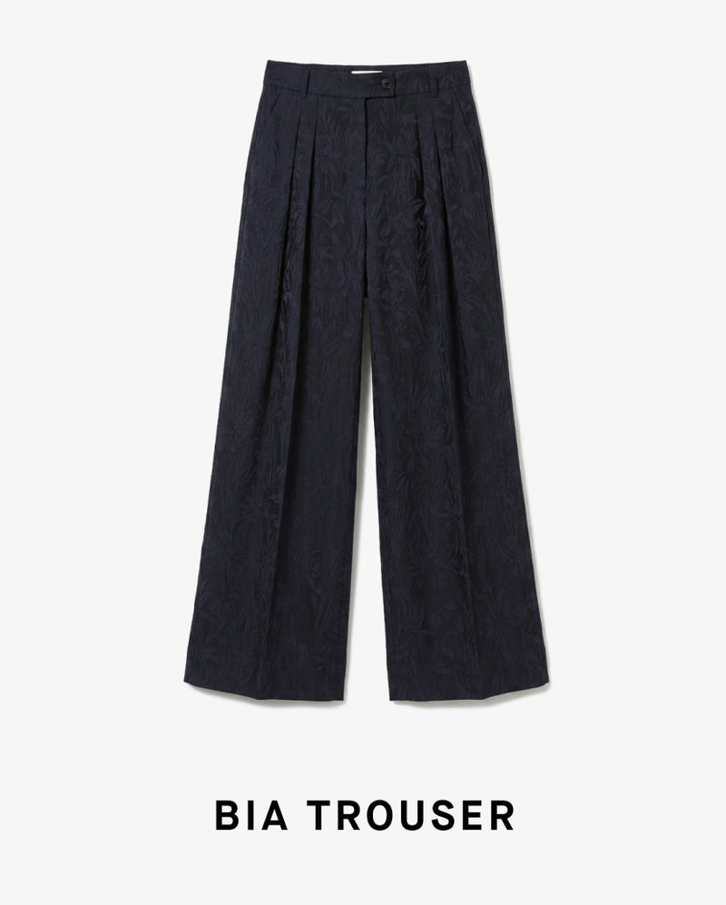 Black pleated trousers on a white background with 'BIA TROUSER' text.