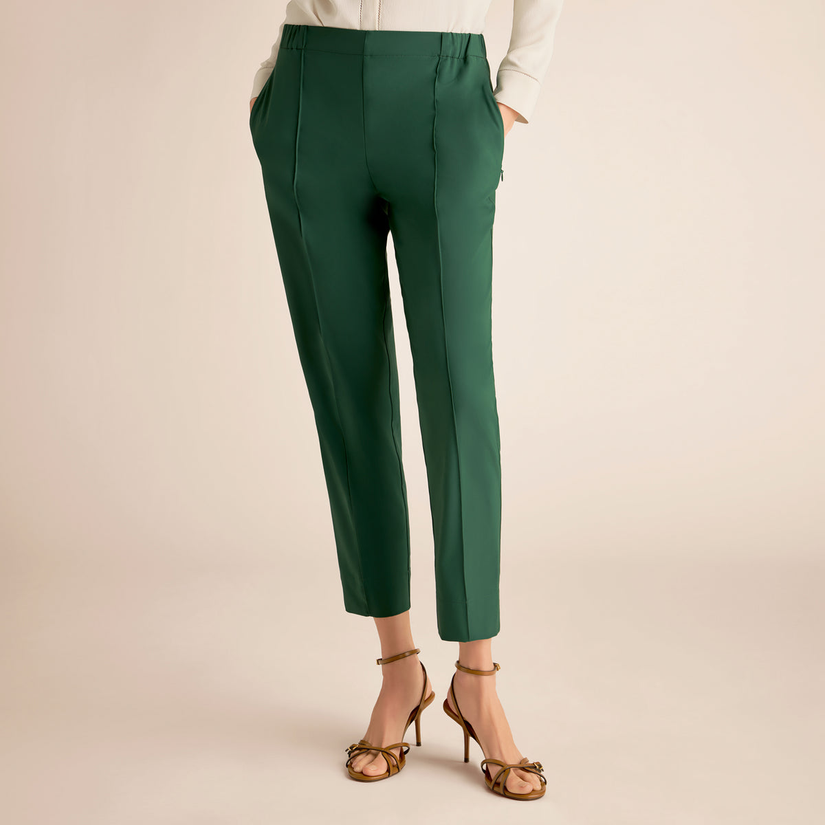 Green pants worn by a person on a beige background