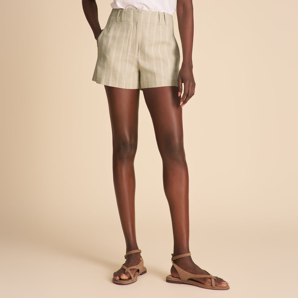 Person wearing light green shorts and sandals on a beige background
