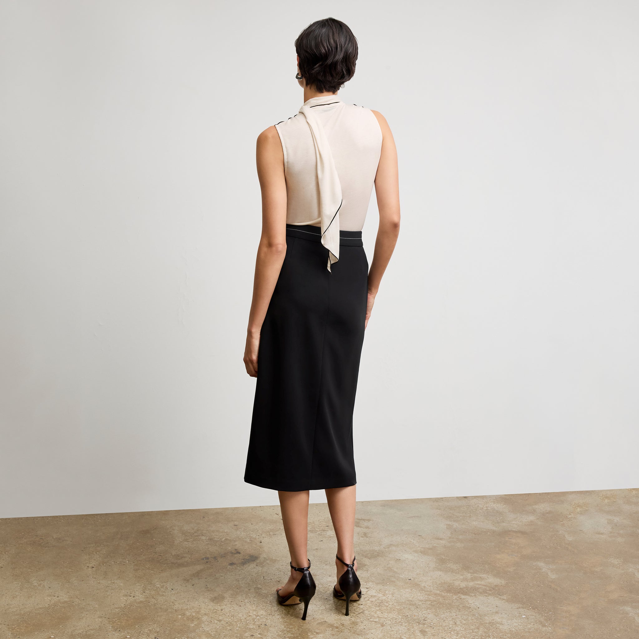 back image of a woman wearing the meghan skirt in black with topstitch