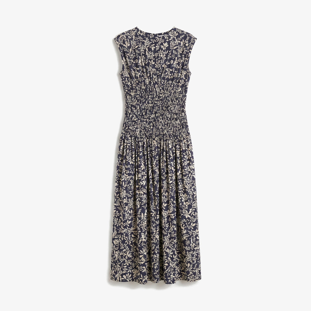 A sleeveless midi dress with a smocked bodice and an all-over abstract floral print in navy blue and cream, shown against a plain light gray background.