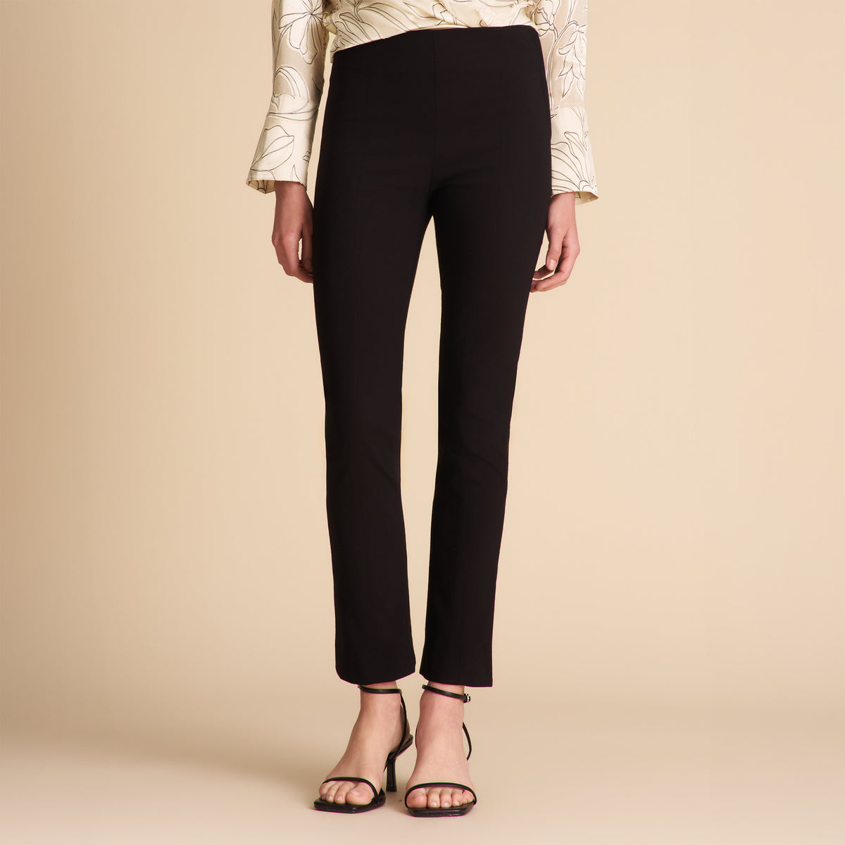 Black pants worn by a person on a beige background