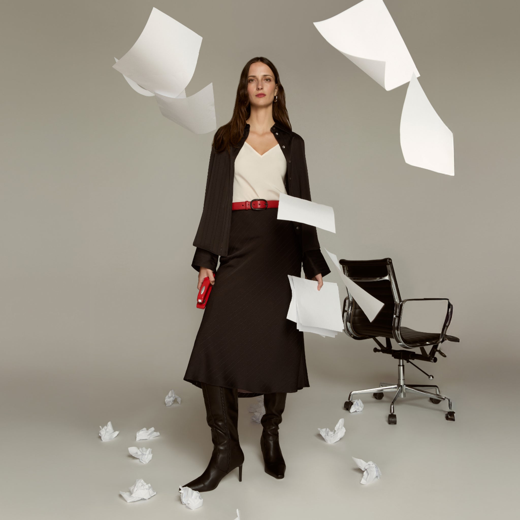 Woman in professional attire with papers and a chair in a minimalistic setting