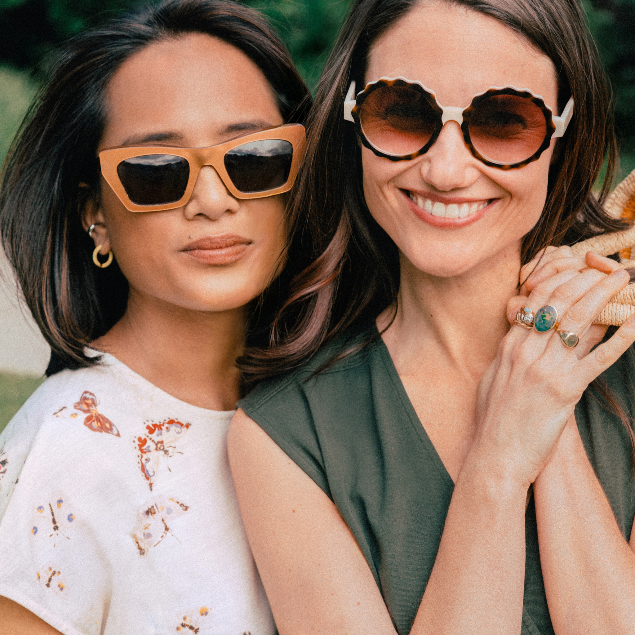 Two women wearing sunglasses and smiling outdoors