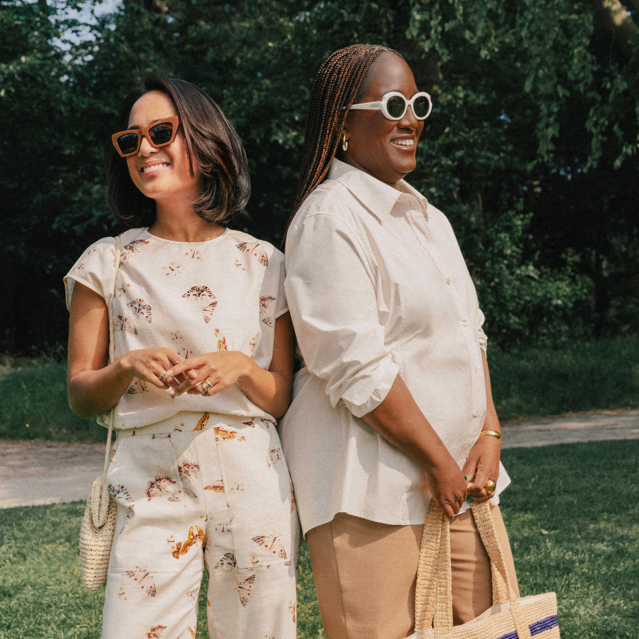 Two women standing outdoors, smiling and wearing sunglasses.