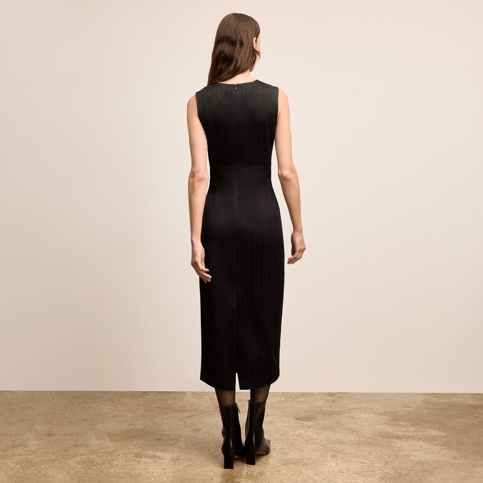 Woman wearing a black sleeveless dress against a beige background