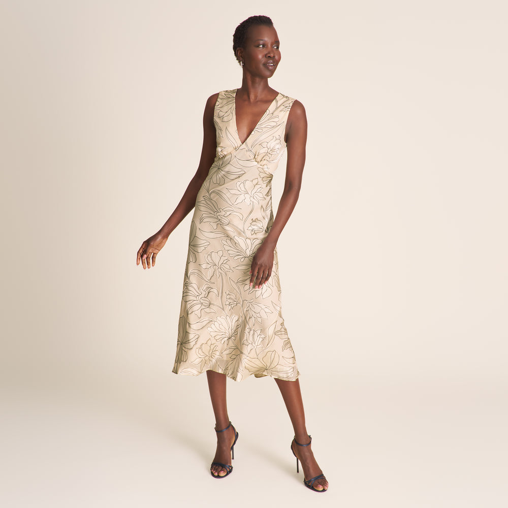 Woman wearing a beige floral dress on a plain background