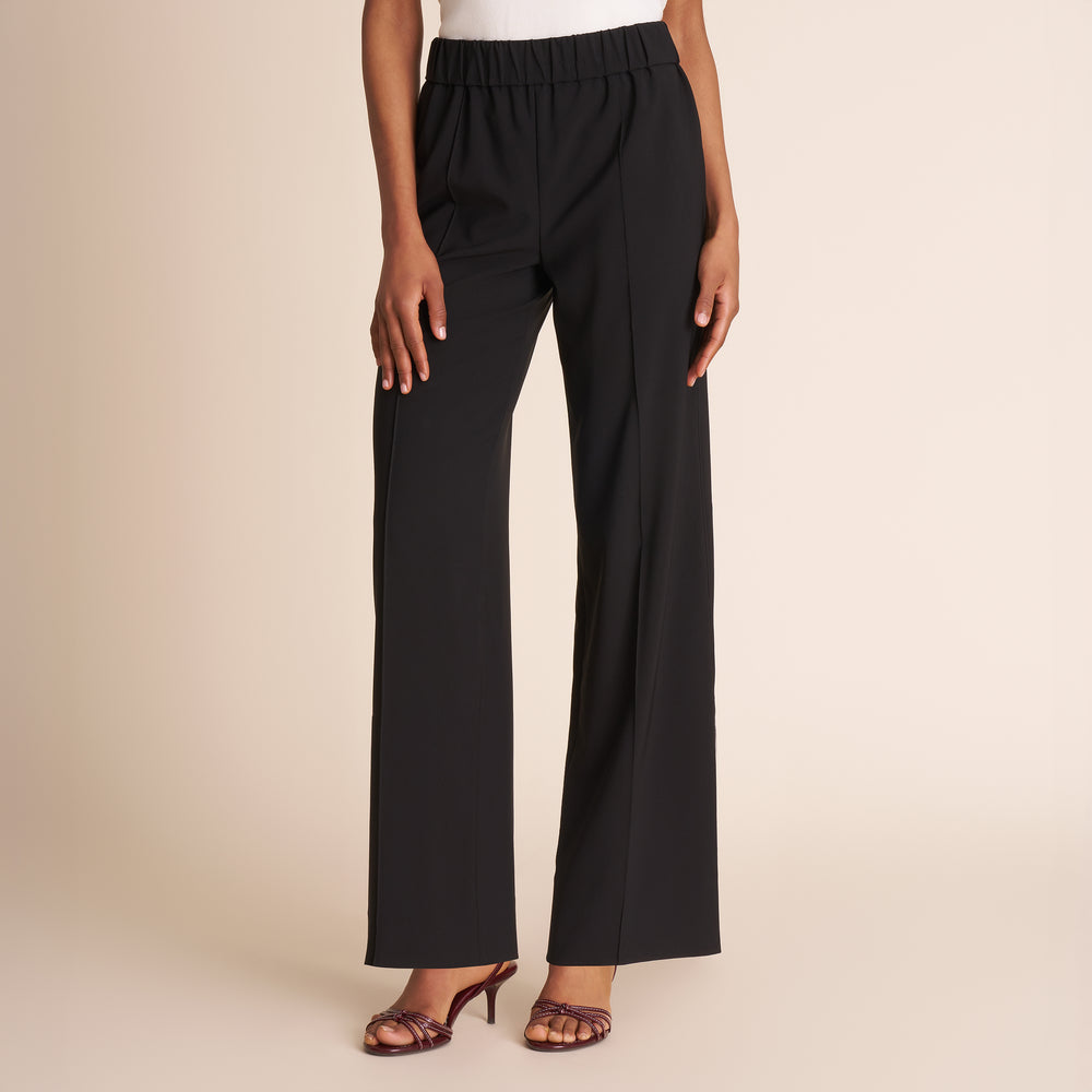 Black pants worn by a person on a beige background