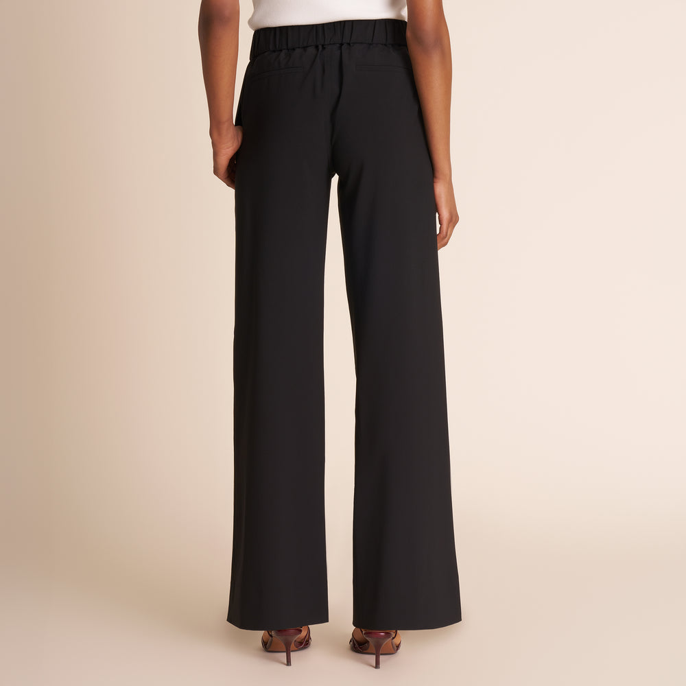 Black wide-leg pants worn by a person on a beige background
