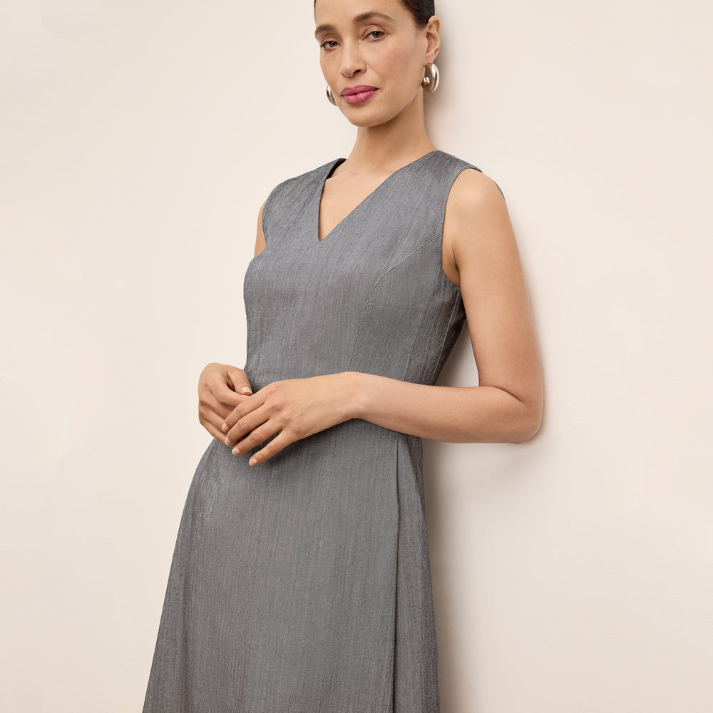 Woman wearing a gray sleeveless dress against a beige background