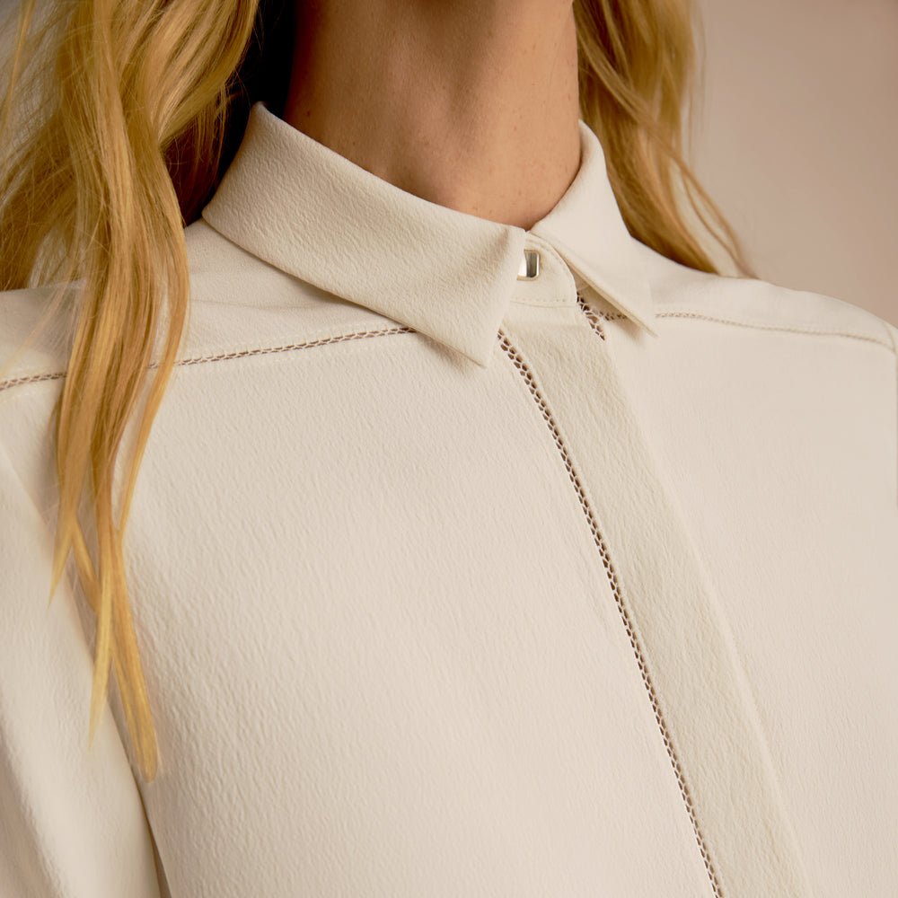 Close-up of a person wearing a beige jacket with a zipper.