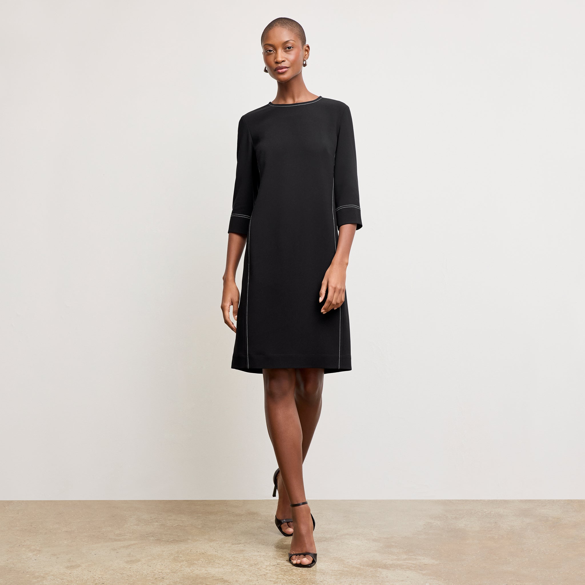 front image of a woman wearing the lancia dress in black with topstitch 