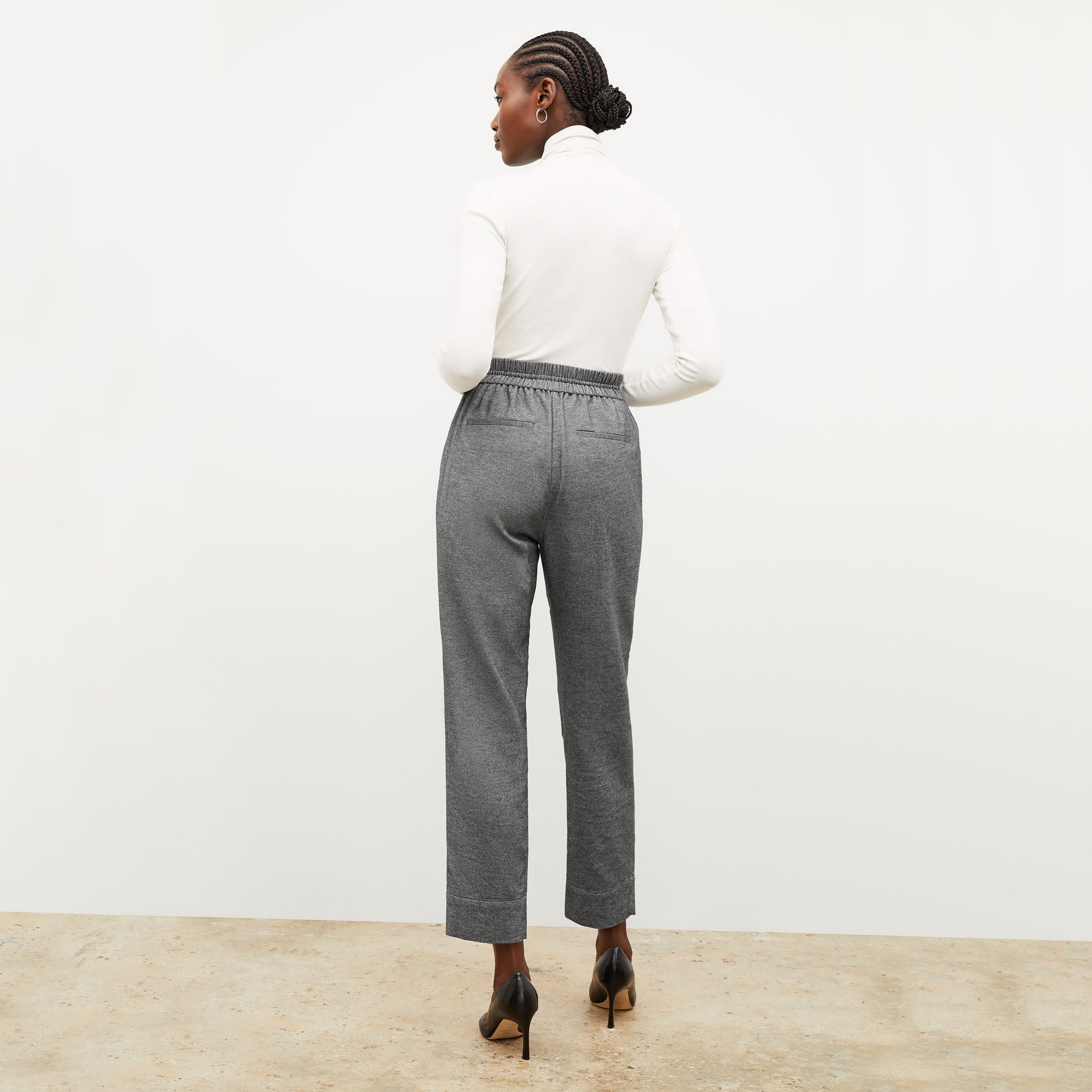 Back image of a woman standing wearing the axam top in ivory