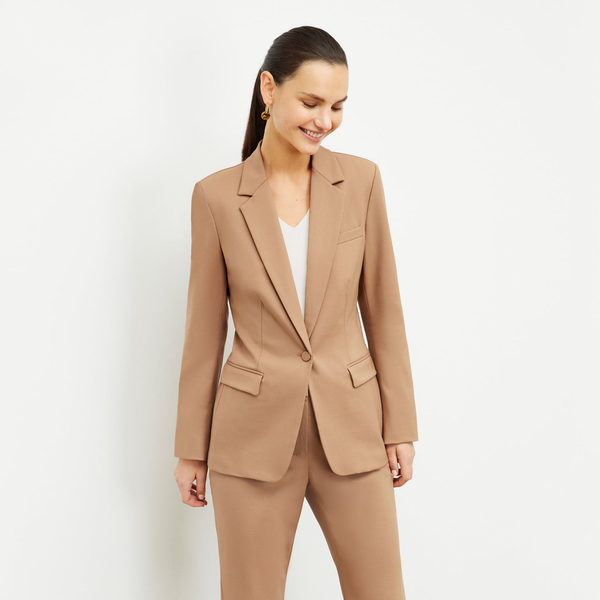 Front image of a woman standing wearing the Yiyan Blazer in Camel 