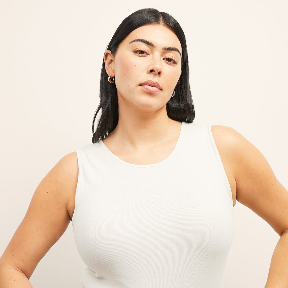 Front image of a woman standing wearing the paige top in fine ribbed cotton in ivory