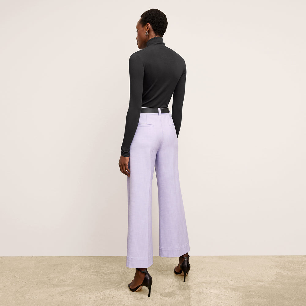Back image of a woman standing wearing the axam top in black