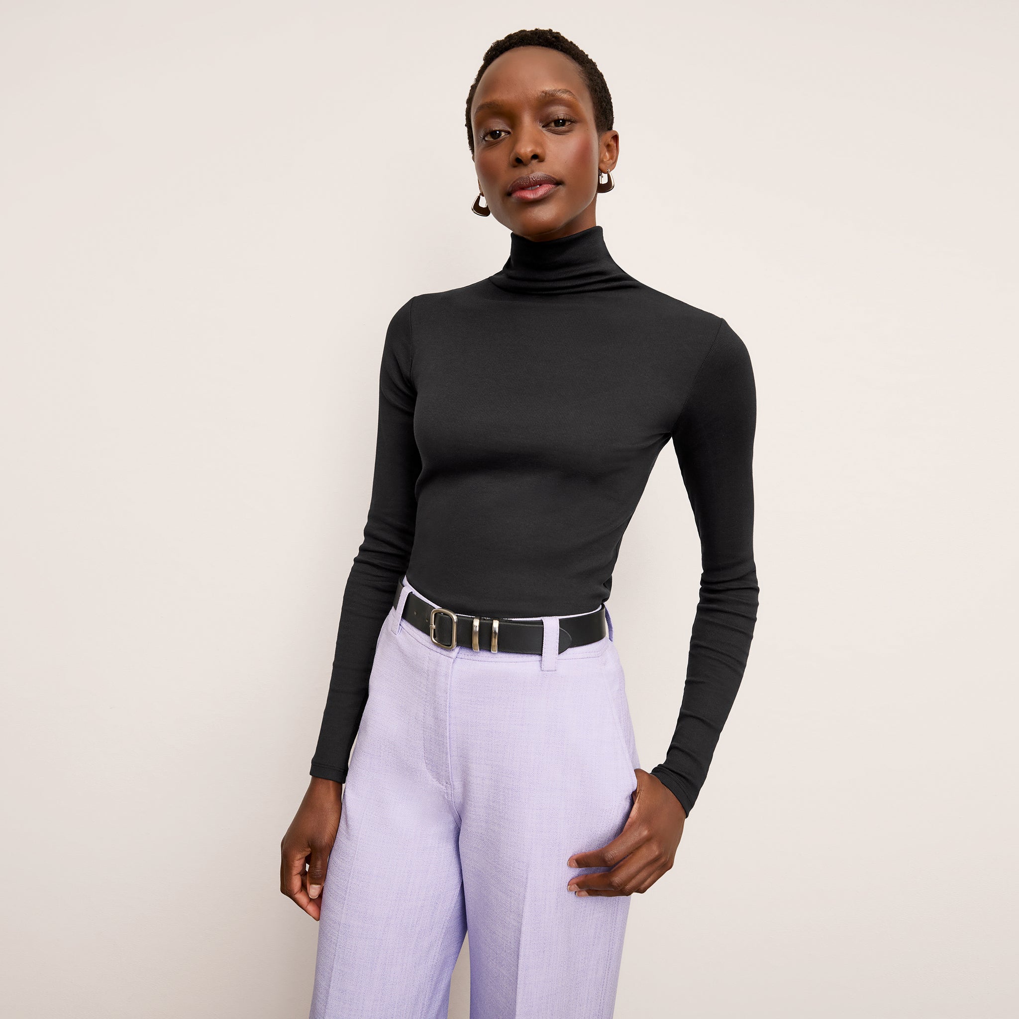 Front image of a woman standing wearing the axam top in black