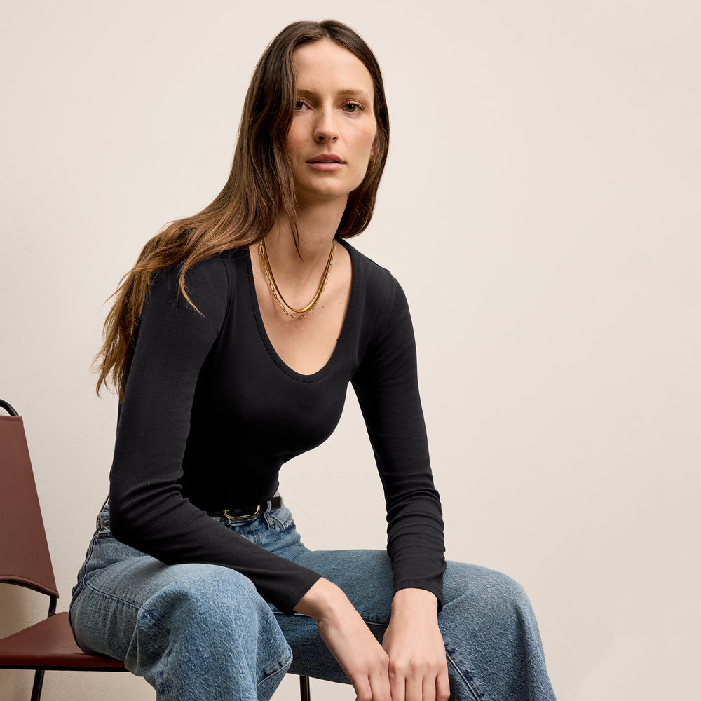 Front image of a woman standing wearing the marcia top in fine ribbed cotton in black