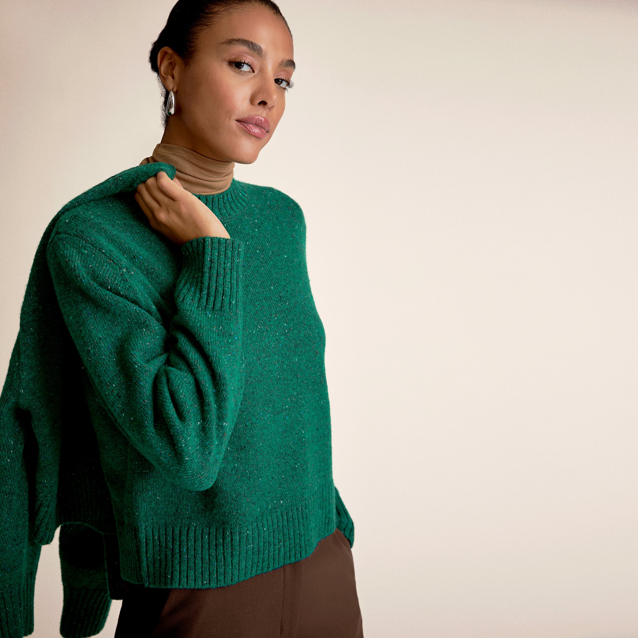 Woman wearing a green sweater with brown pants 