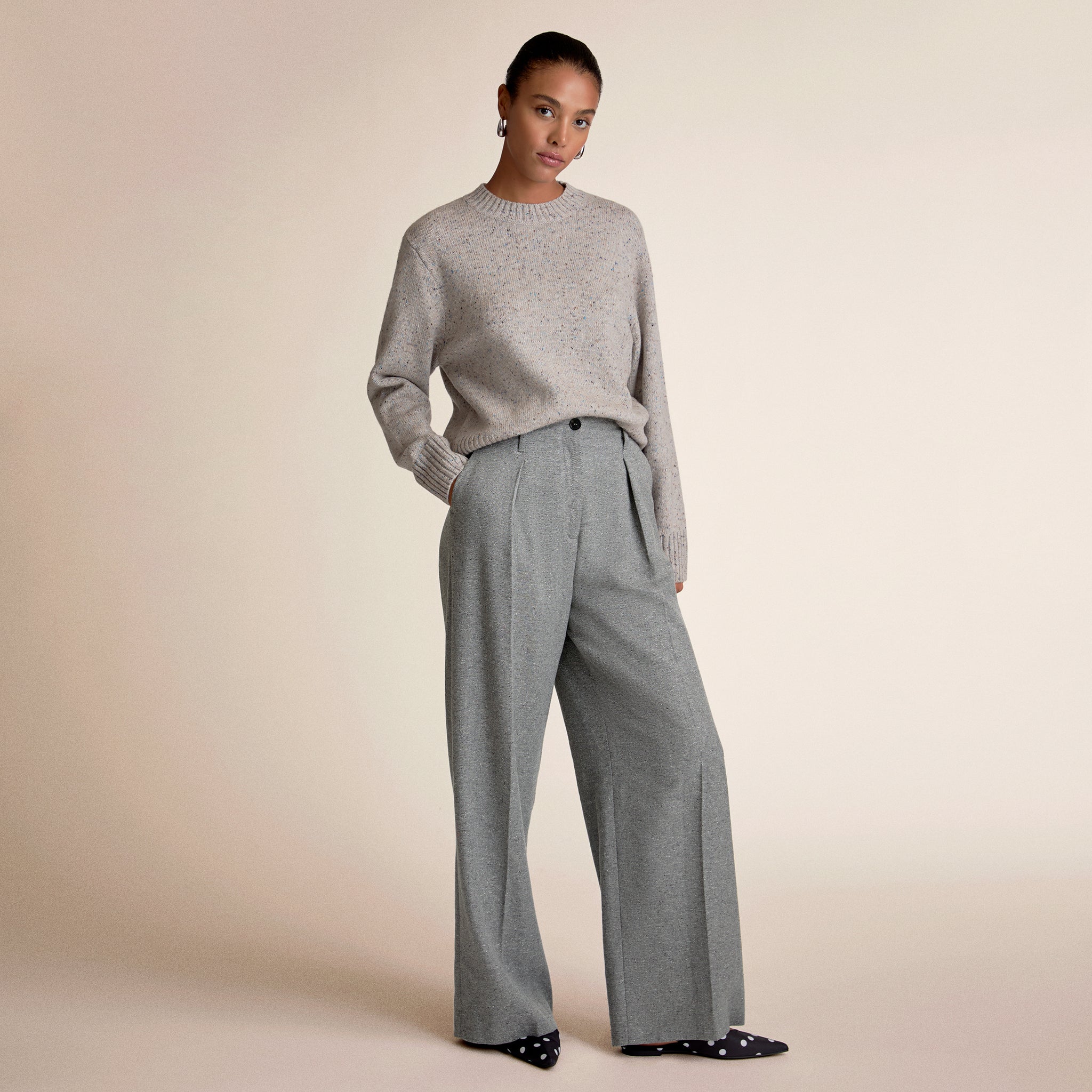 Woman wearing a gray sweater and matching wide-leg pants on a beige background