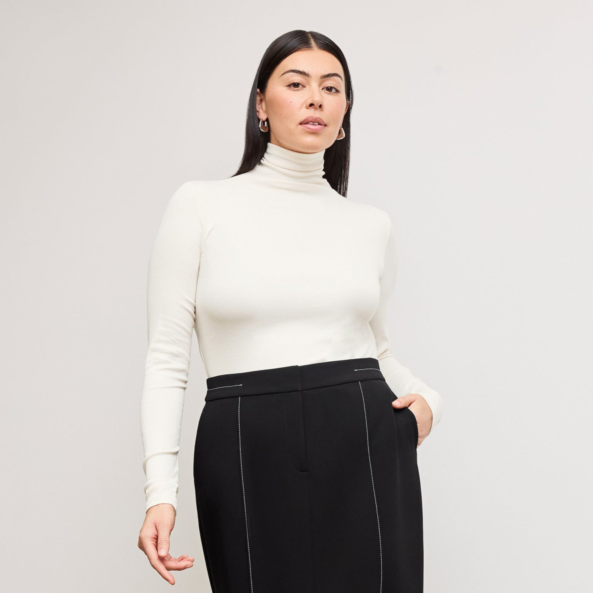 Front image of a woman standing wearing the axam top in ivory 