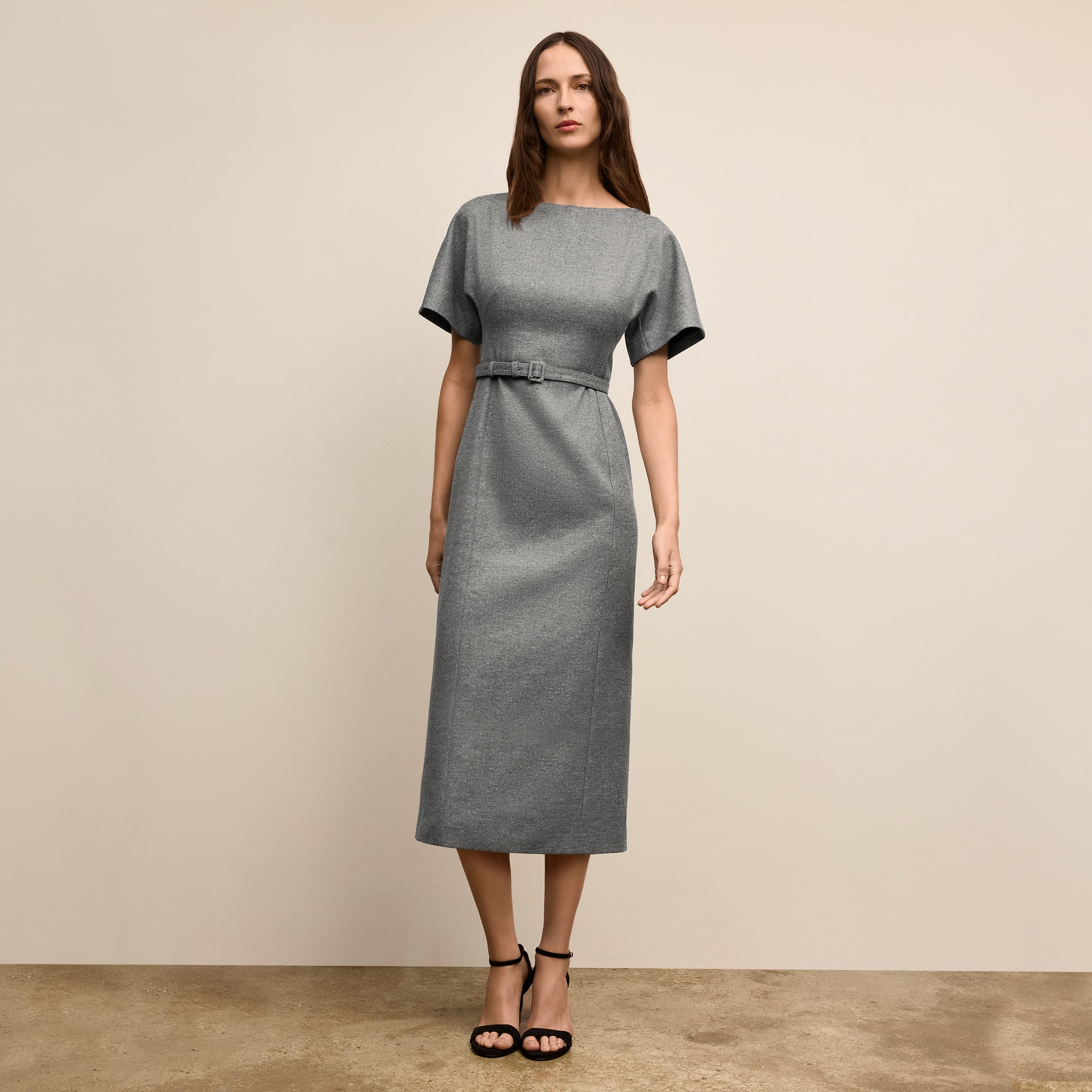 Woman wearing a gray dress against a beige background 