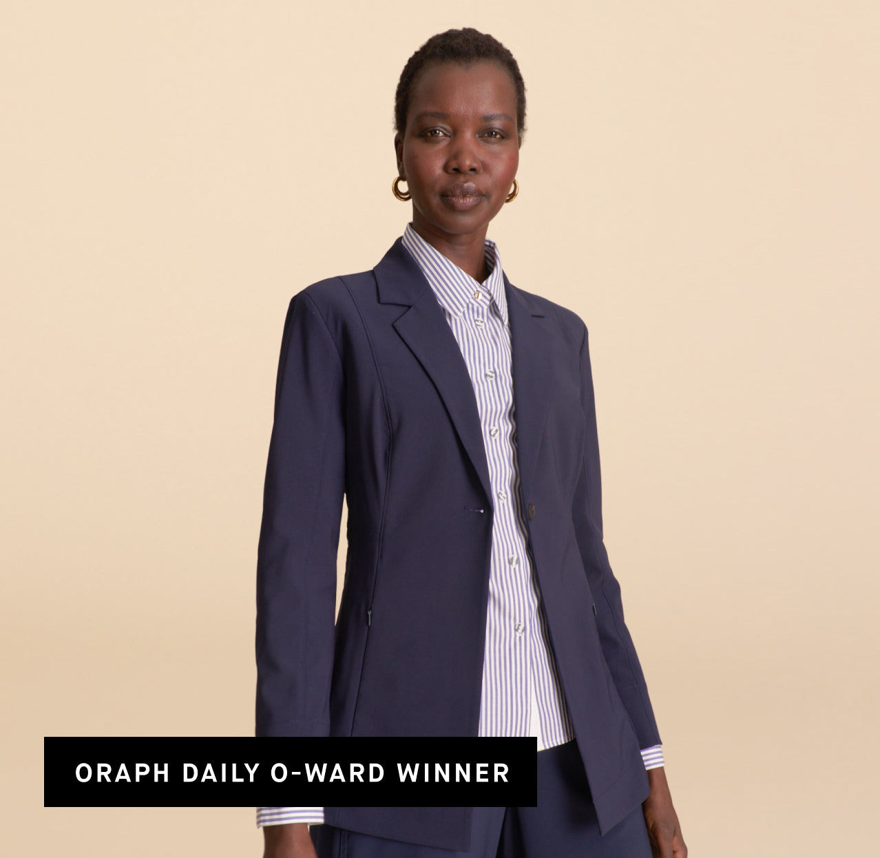 Woman wearing a navy blazer over a striped shirt on a beige background. OPRAH DAILY O-WARD WINNER