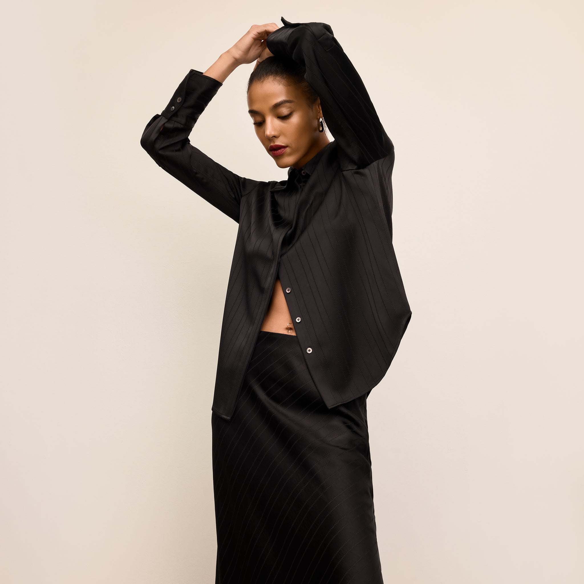 Woman wearing a black outfit against a beige background