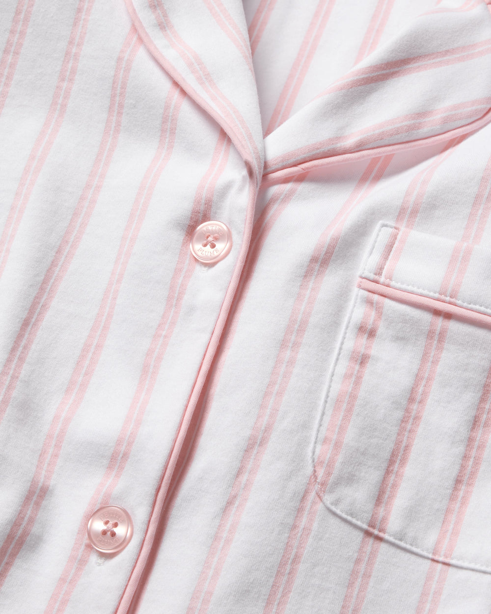 Close-up of a white shirt with pink vertical stripes and buttons.