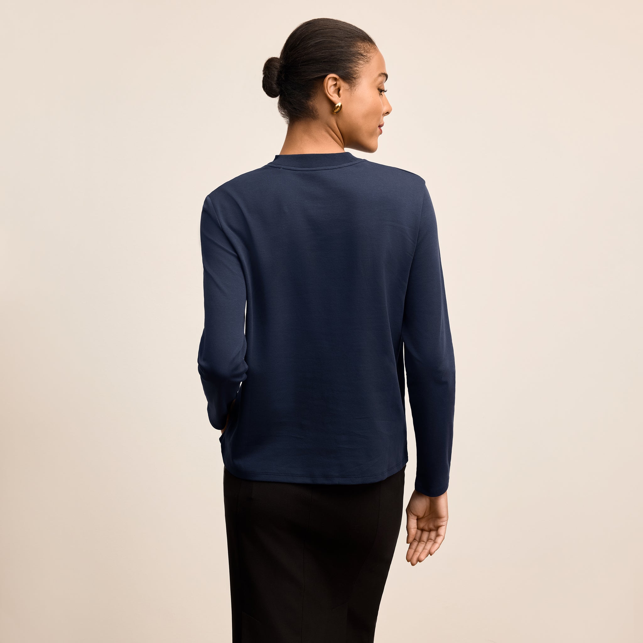 Person wearing a navy long-sleeve shirt on a beige background