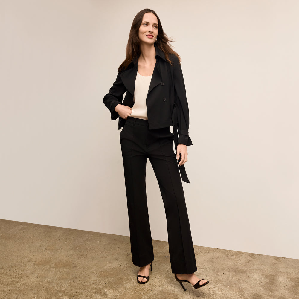 Woman wearing a black suit standing against a plain background