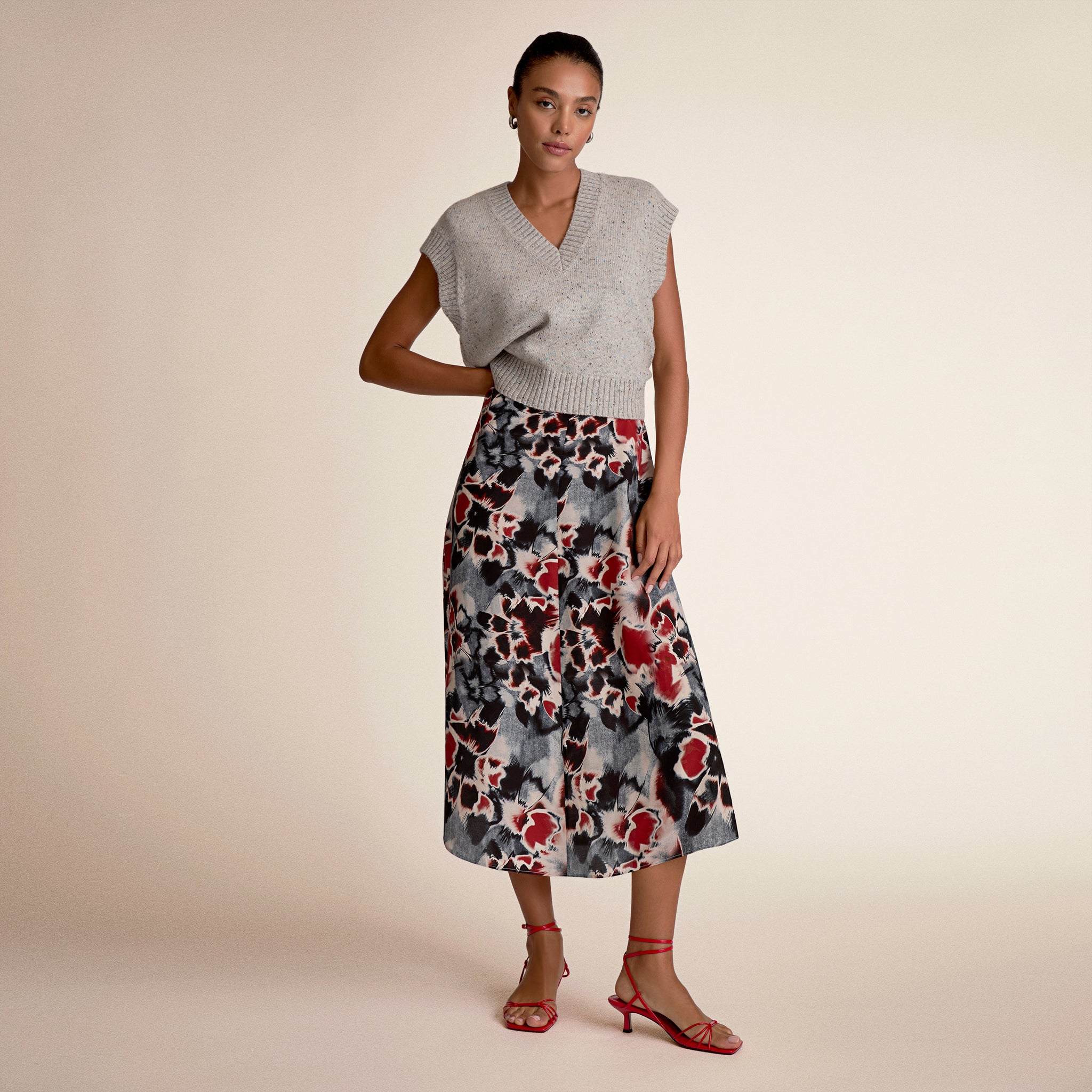 Woman wearing a gray sleeveless top and floral skirt on a beige background