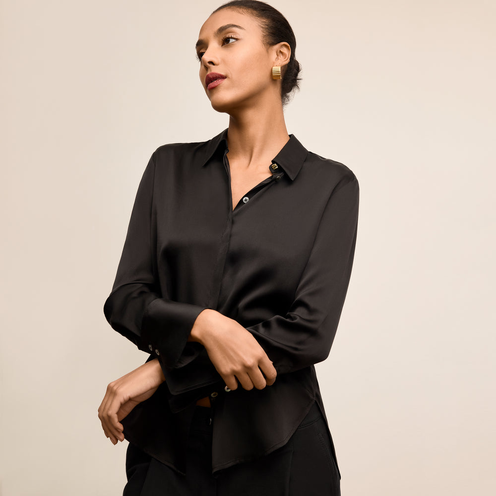 Woman wearing a black blouse against a beige background