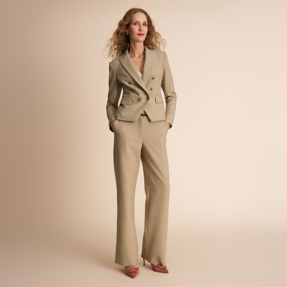 Woman wearing a beige suit against a beige background
