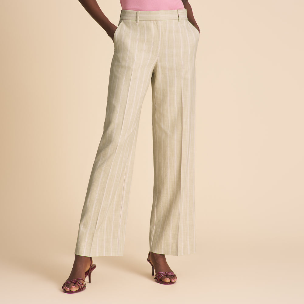 Woman wearing light green pleated pants on a beige background