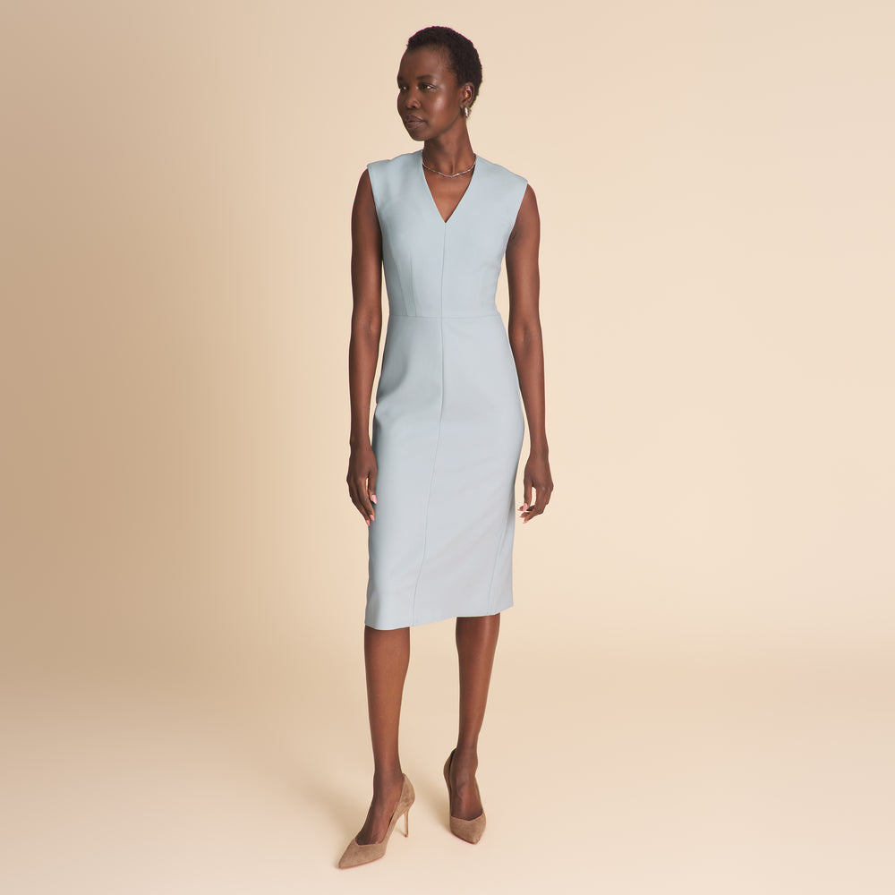 Woman wearing a light blue v neck dress on a beige background