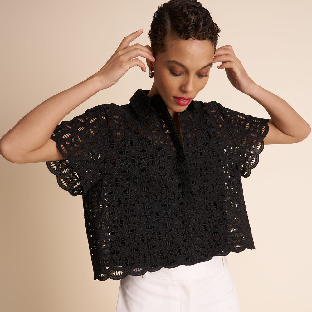 Woman wearing a black lace top against a beige
