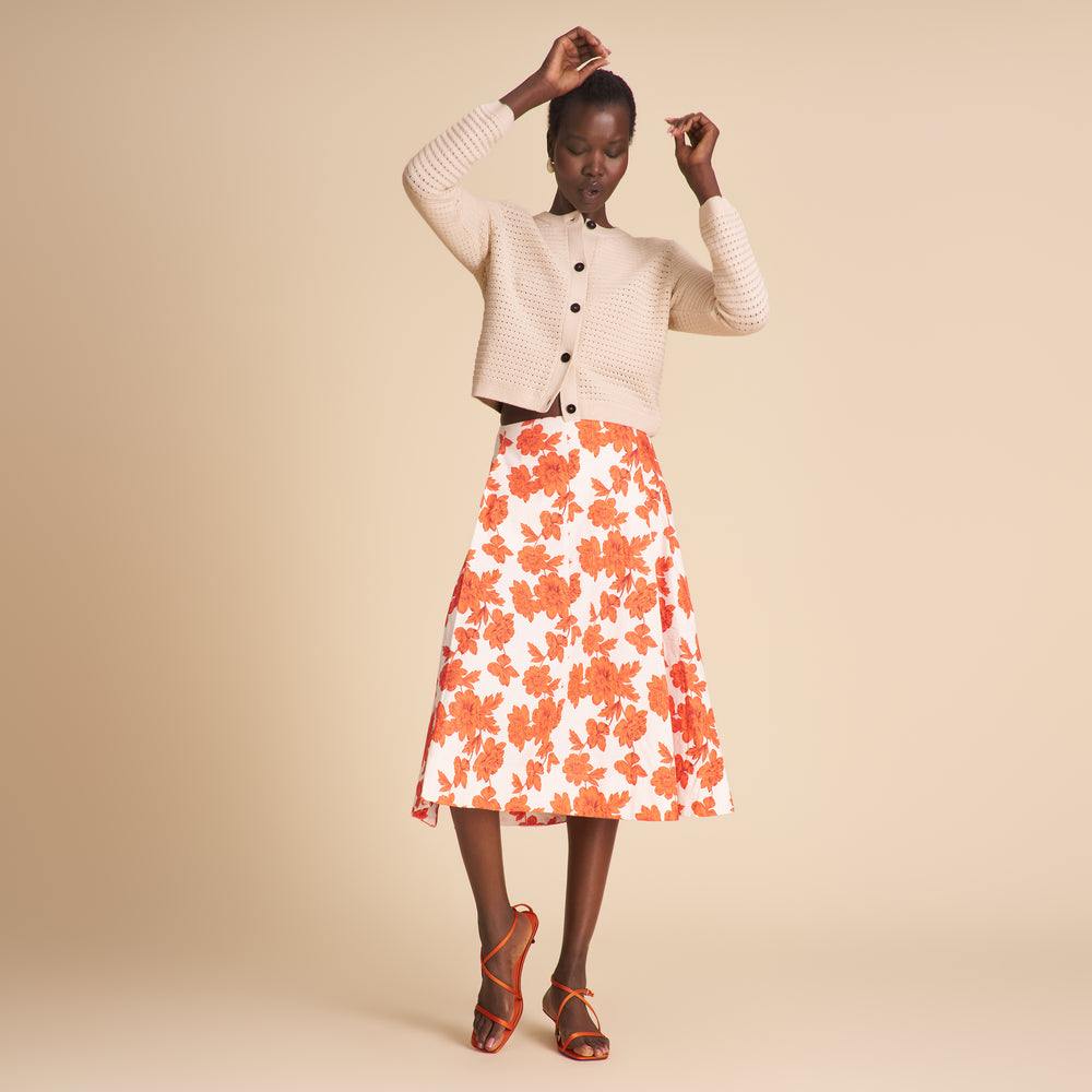 Woman wearing a floral skirt and beige cardigan on a beige background