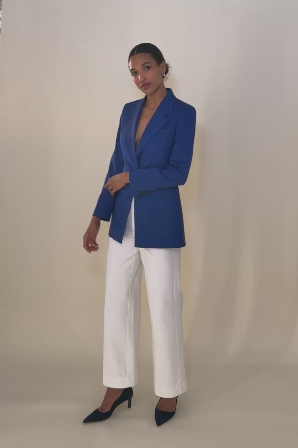 Woman wearing a blue suit with a white top on a beige background