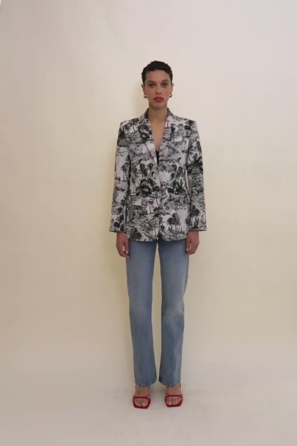 woman in palm print blazer and blue jeans.