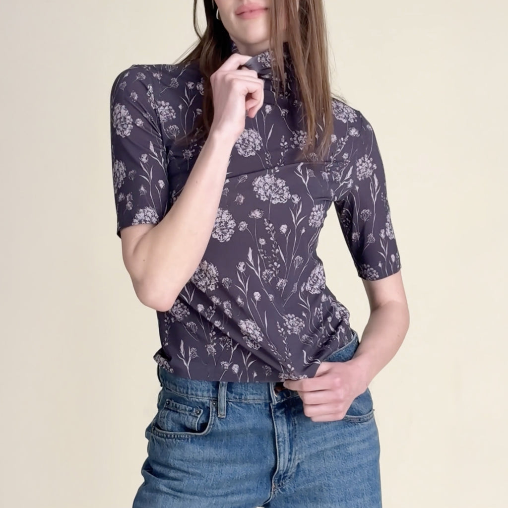 woman in purple pattern turtleneck and blue jeans.