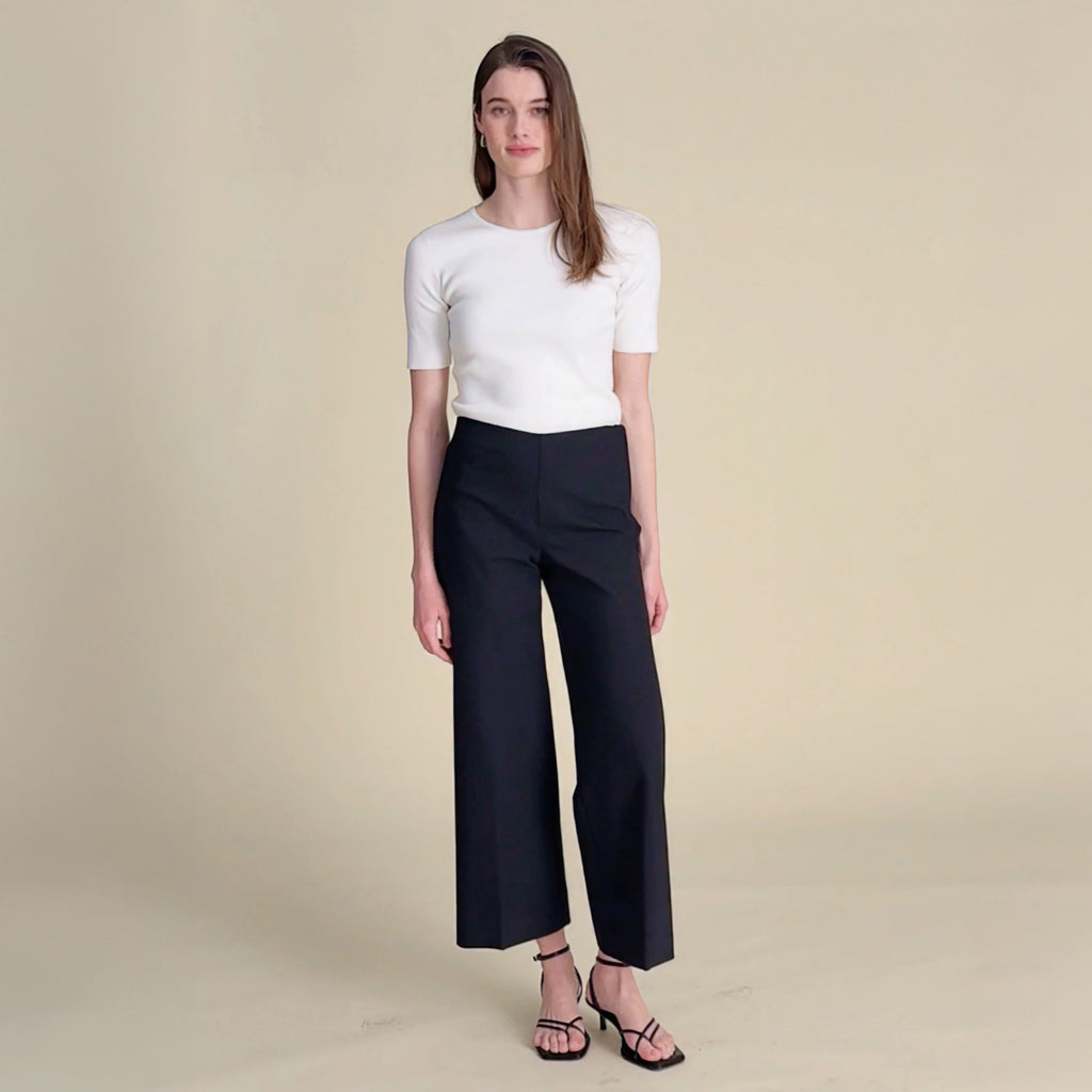 woman in white top and black pants.