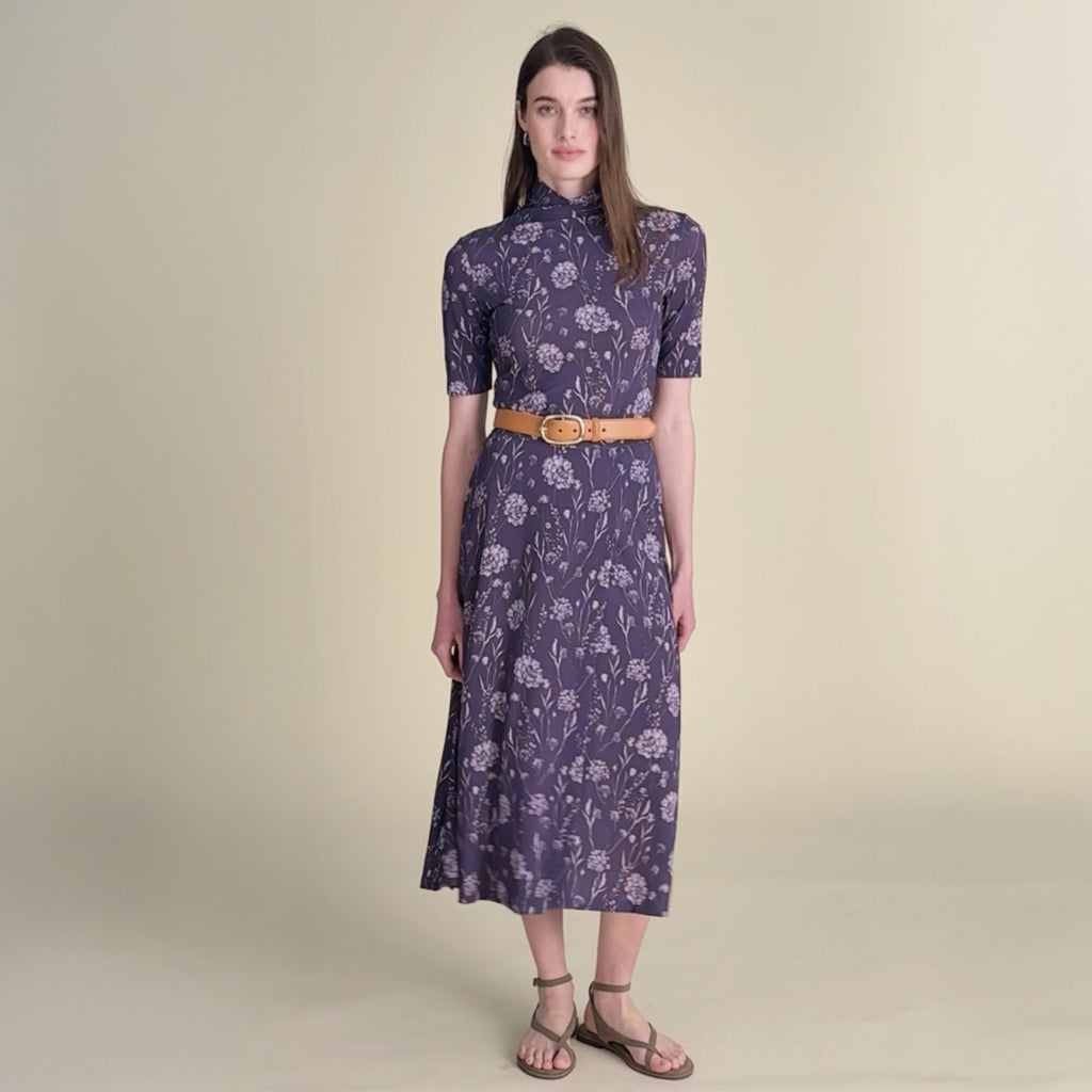 woman in purple pattern turtleneck with matching skirt