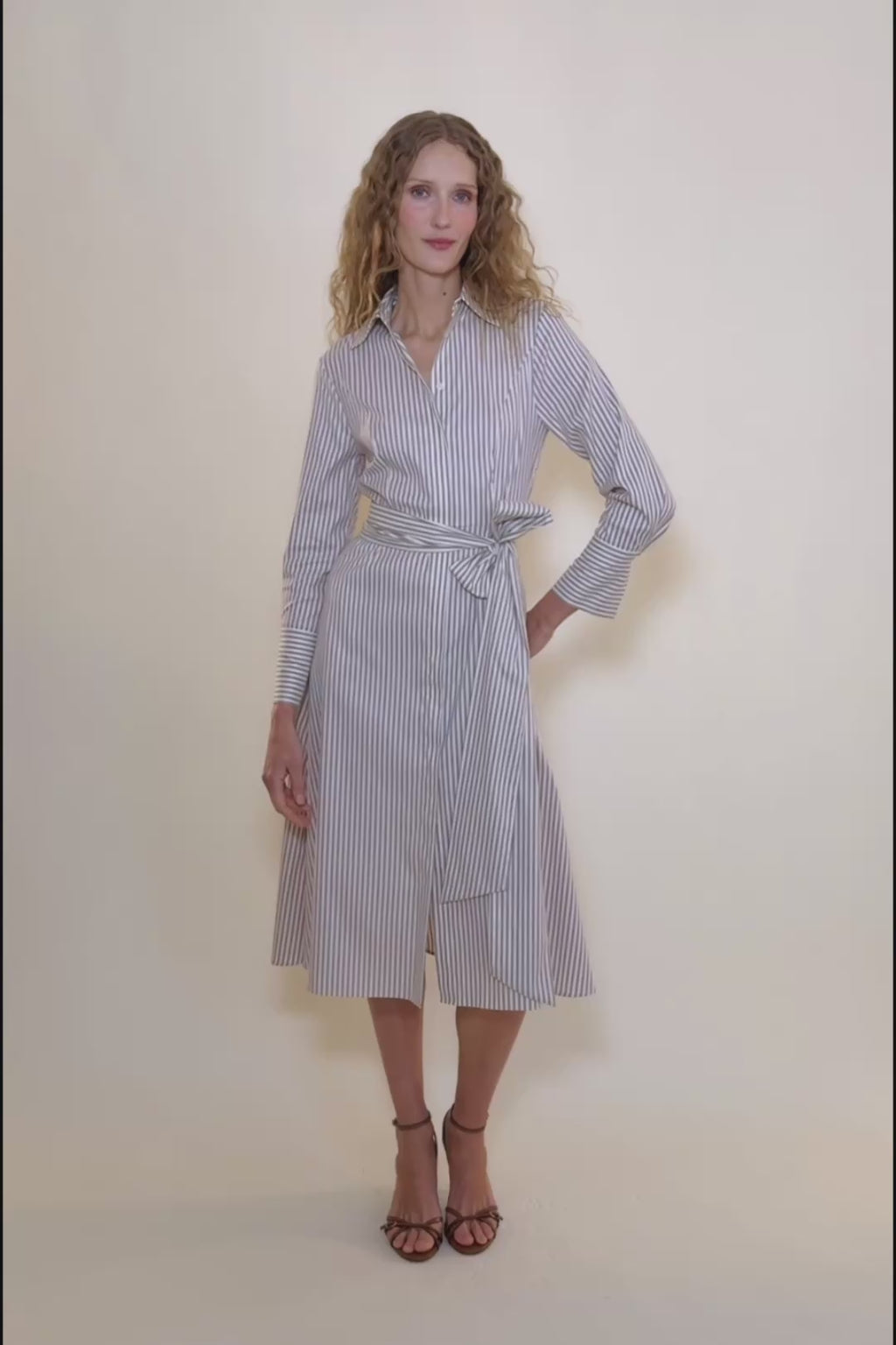 Beige and white striped dress with a tie waist on a beige background.