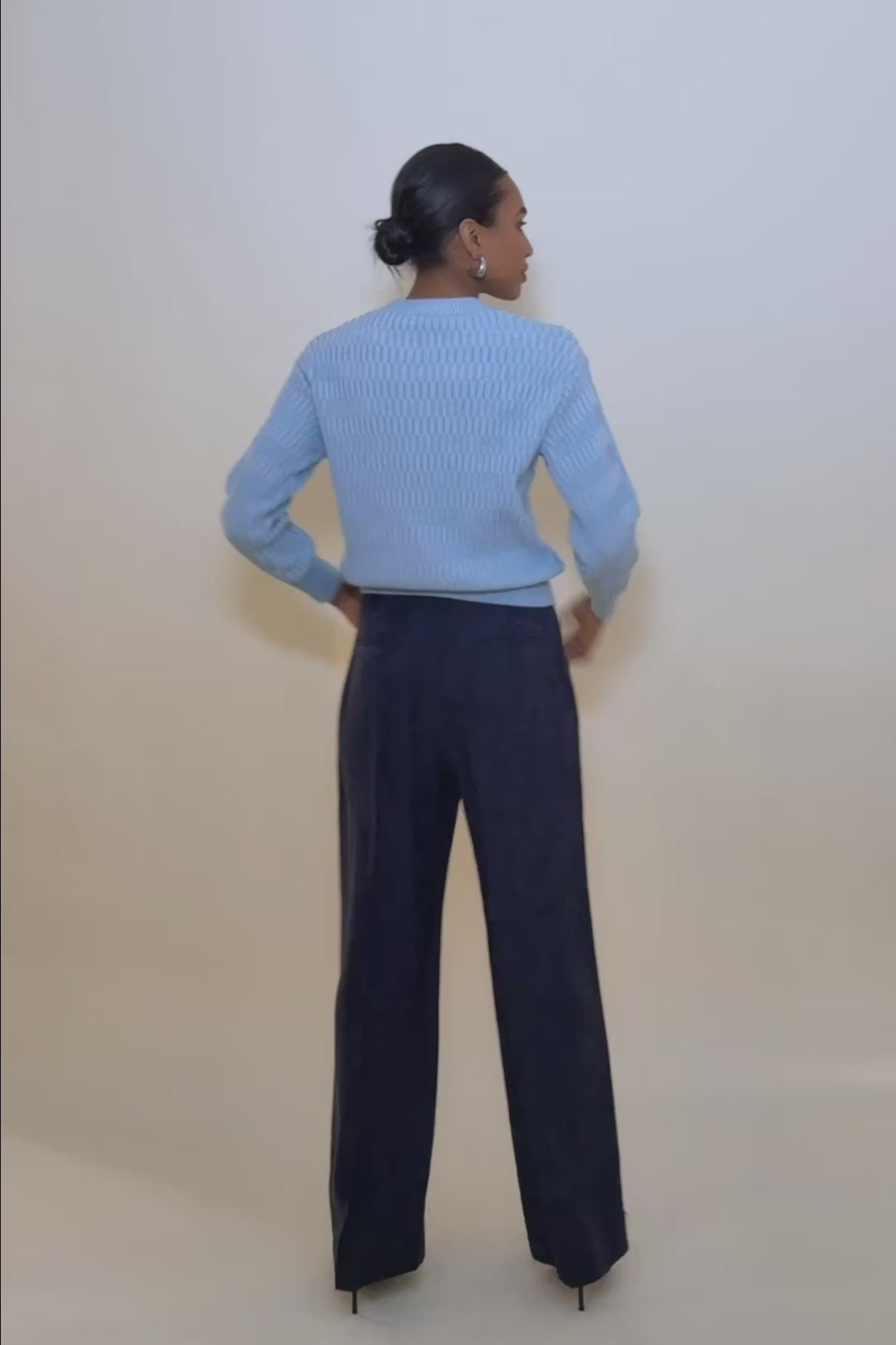 Video of a woman wearing the Maura sweater in blue and showing the stretch of the knit. 