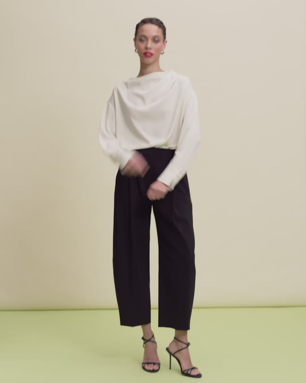 video of a woman wearing an ivory blouse and black pants